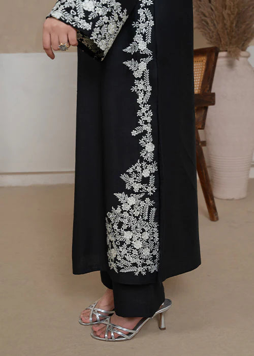 Close-up of vibrant pink and green floral embroidery on black sleeves.