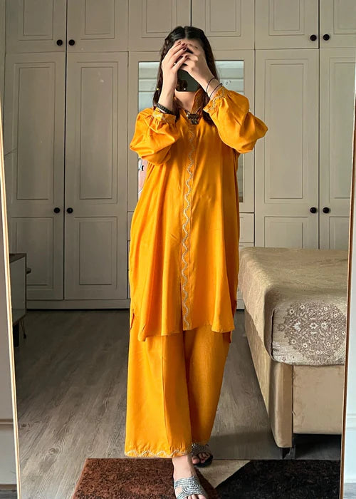 Intricate wavy ivory embroidery on the cuffs of a yellow shirt.