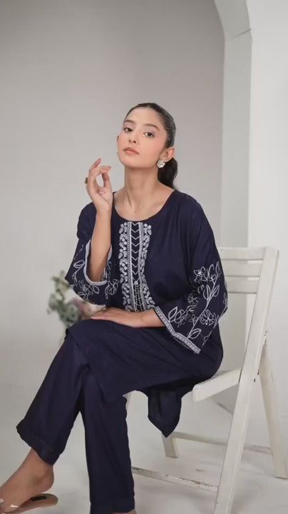 Close-up of silver-white geometric and floral embroidery on a navy blue neckline.
